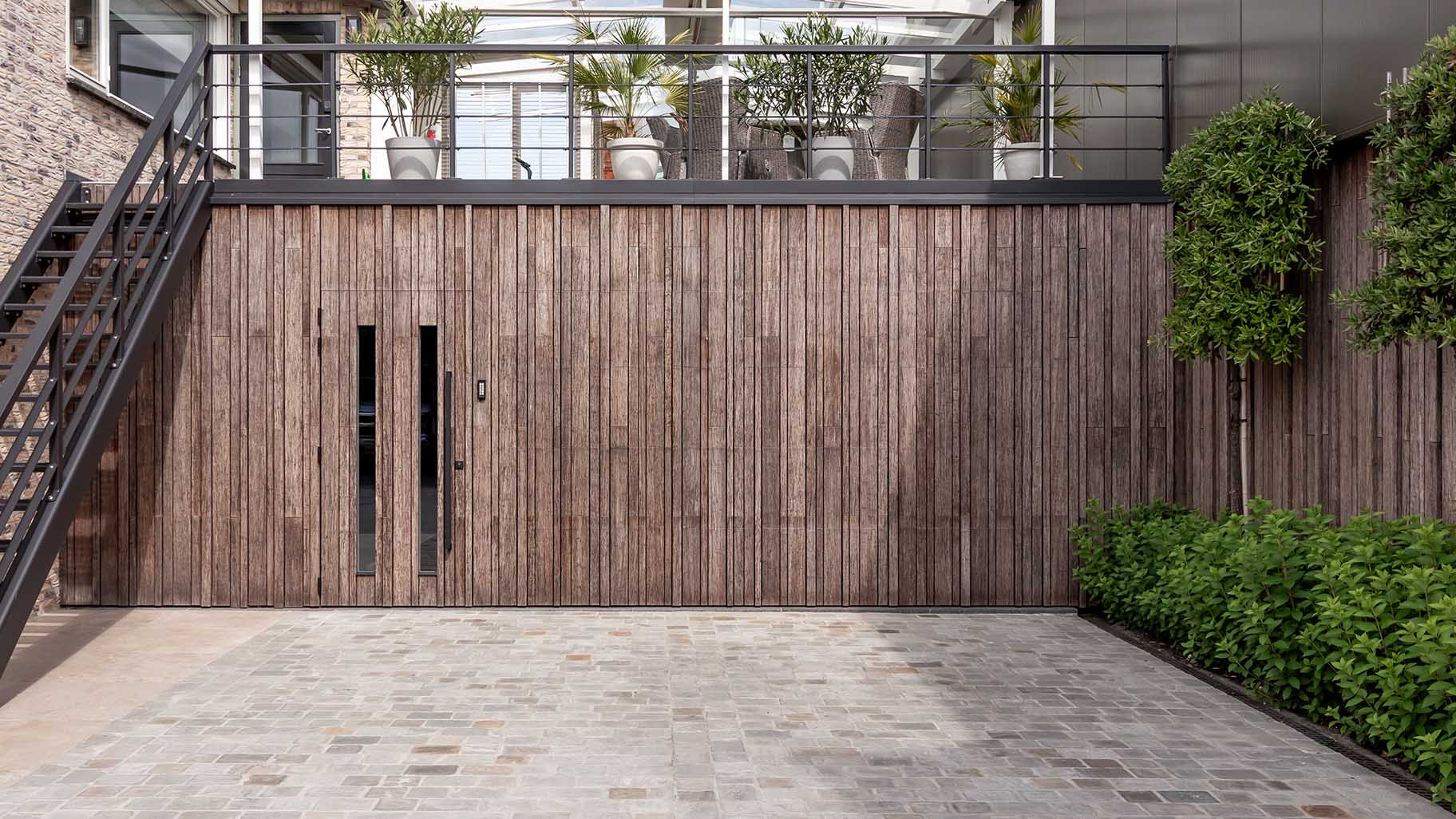 Bamboo garage door and pivot door flush with the facade