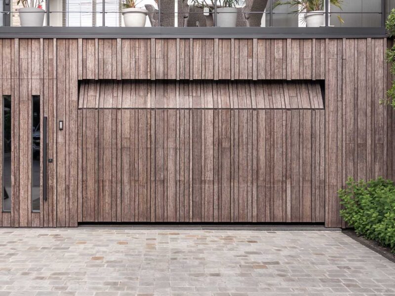Bamboo garage door and pivot door flush with the facade