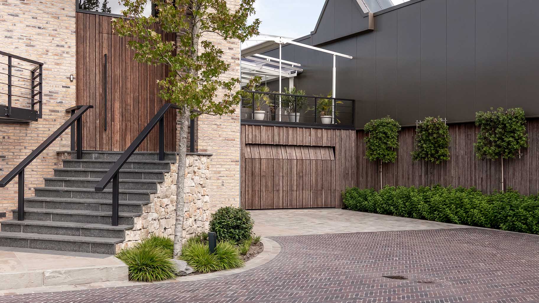 Bamboo garage door and pivot door flush with the facade