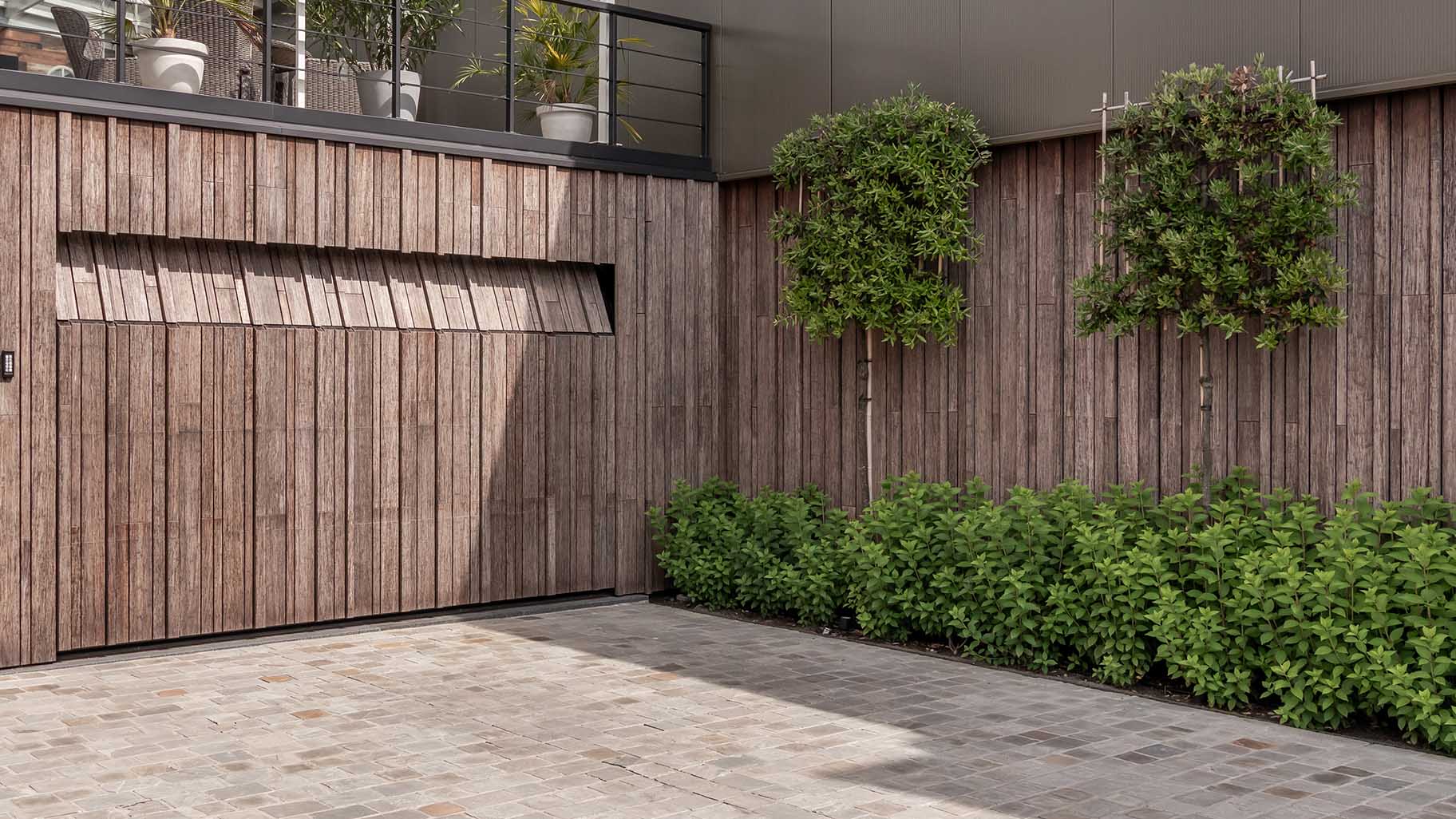 Bamboo garage door and pivot door flush with the facade