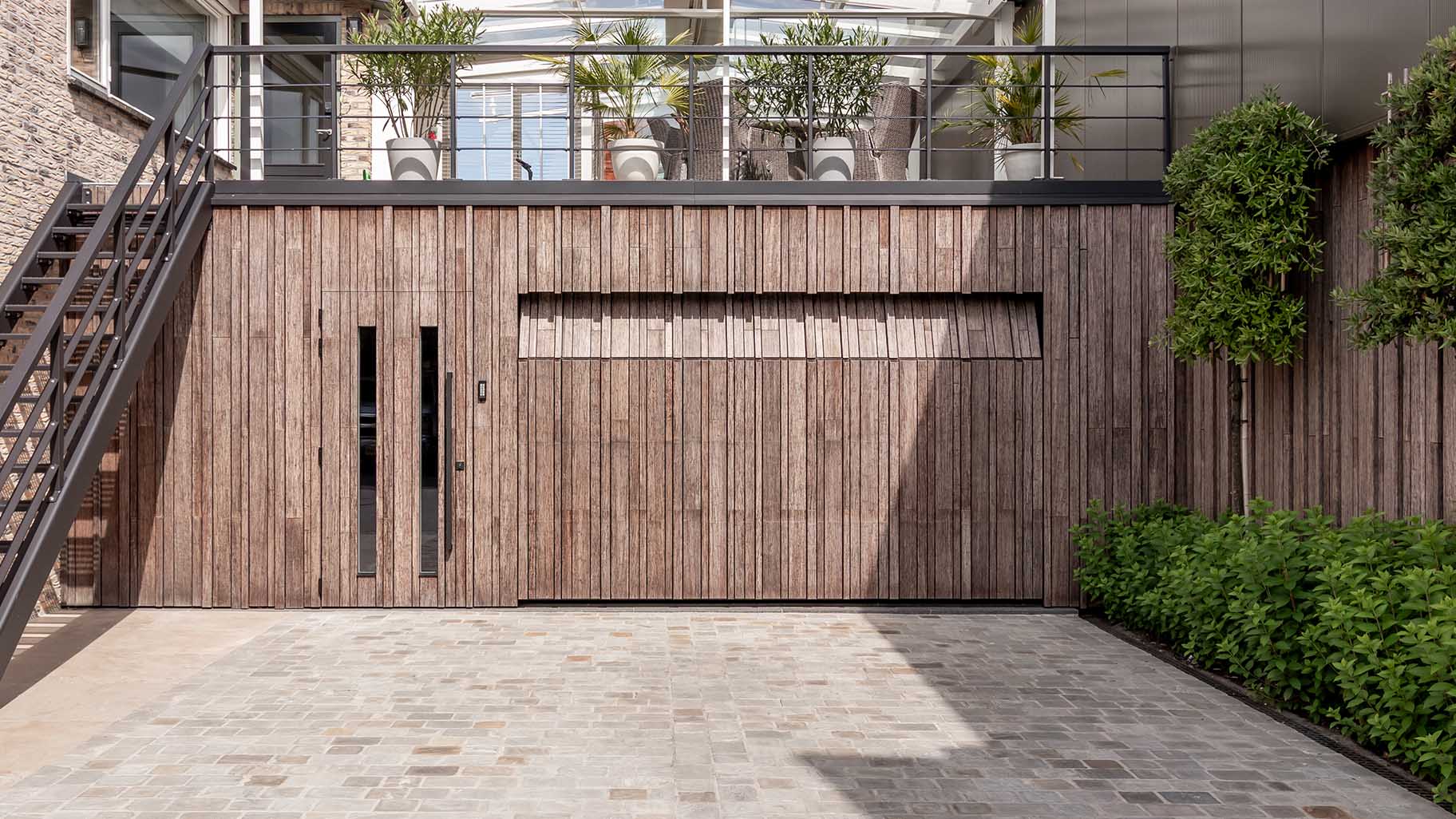 Bamboo garage door and pivot door flush with the facade