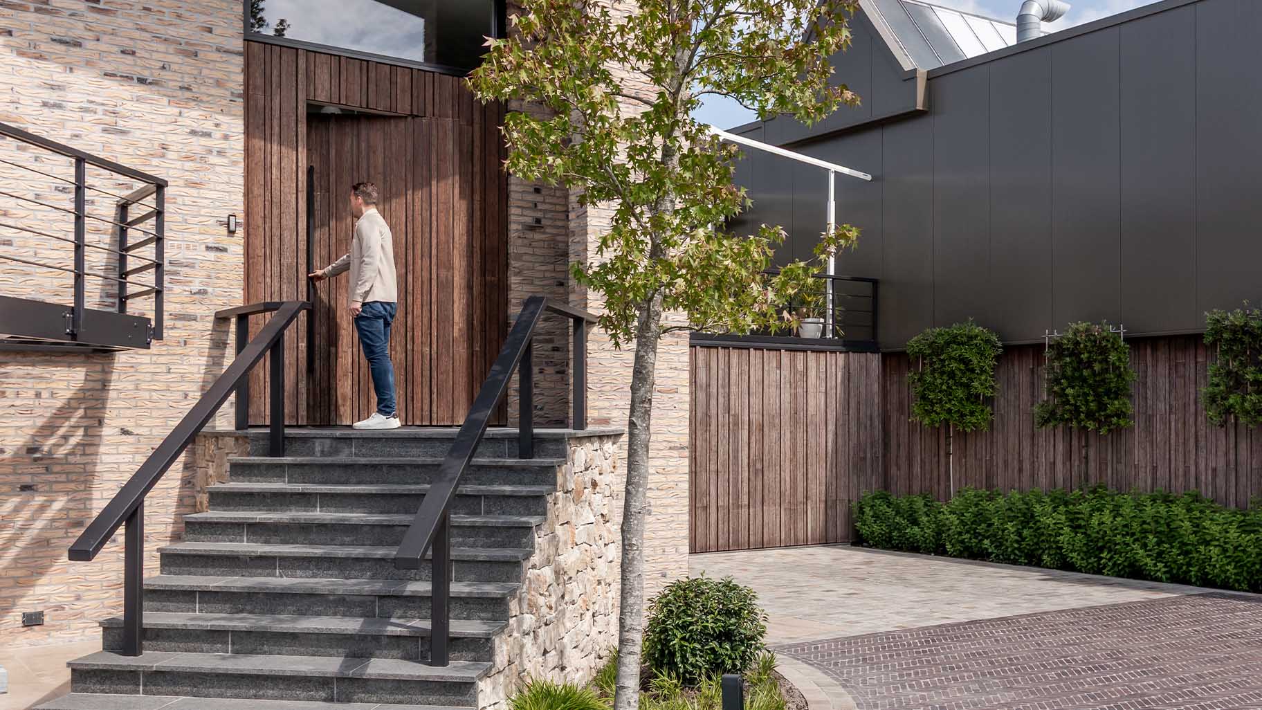 Bamboo garage door and pivot door flush with the facade