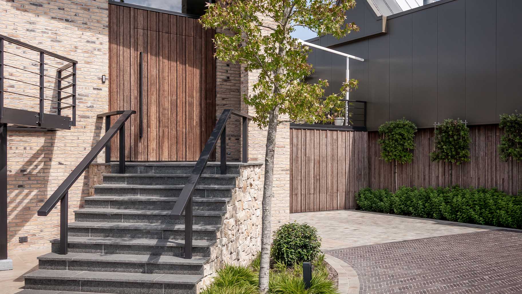 Bamboo garage door and pivot door flush with the facade