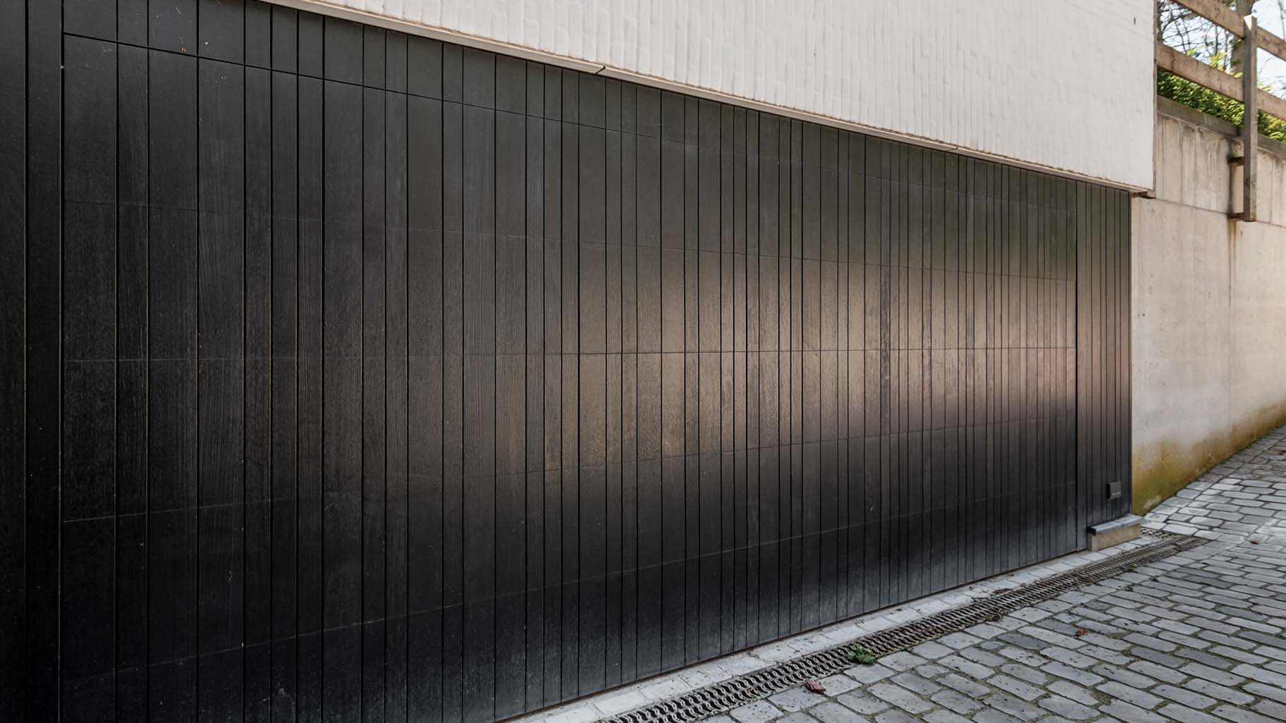 Dark wooden garage door flush with the facade