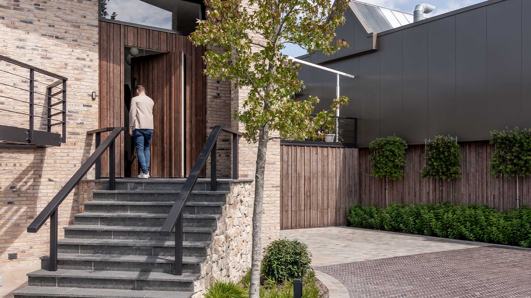 Bamboo garage door and pivot door flush with the facade