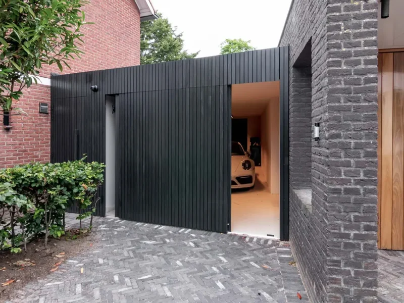 Modern garage with a black Afrormosia side sliding garage door and a Porsche